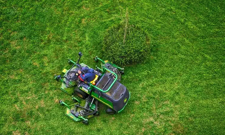 green and black ride on lawn mower on green grass field during daytime